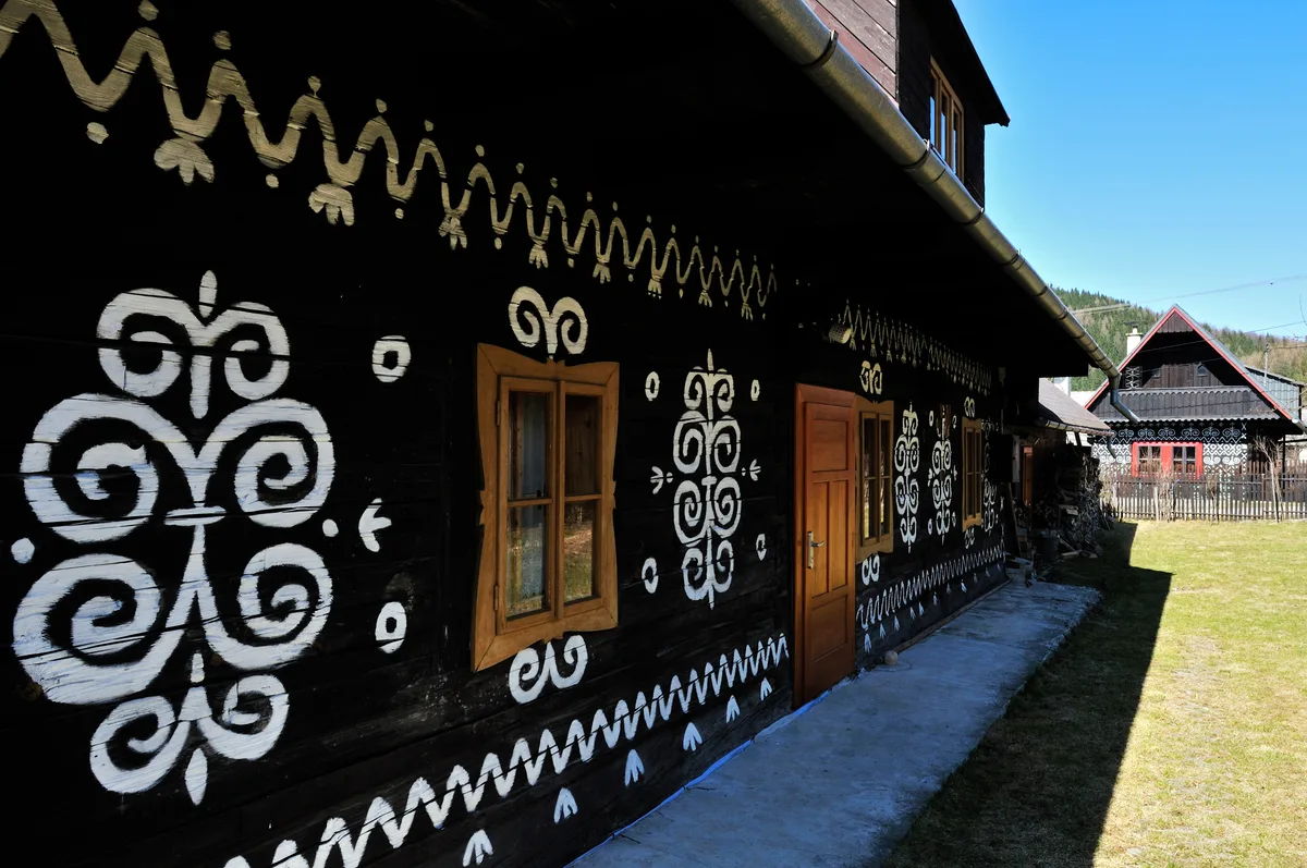 White geometric ornament on a traditional dark timber house in Čičmany, Slovakia